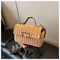 Detail of hand-woven straw crossbody bag with dark brown leather trim and metal clasp - Brown