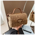 Close-up of woven straw handbag with a gold square metal lock and leather strap detail - Khaki