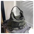 Macro detail of olive green nylon tote bag showing pockets and durable fabric texture - Green