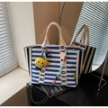 Blue and white striped canvas tote bag with a yellow smiley face charm and lettered handle - Blue