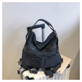 Detail of black nylon tote bag with multiple zipper pockets on a white suitcase - Black