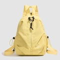 Detail of yellow nylon backpack featuring vertical zipper and water-resistant fabric texture - Yellow