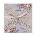 Detailed laser-cut ivory wedding invitation with floral insert and cream satin ribbon bow - Ivory