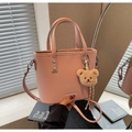 Gros plan détaillé du sac seau rose grainé avec breloque d'ours brun mignon - Rose