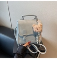 Detail der hellblauen Handtasche mit Krokoprägung, Metallschnallen und Bärenanhänger - Blau mit Anhänger