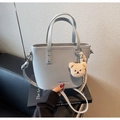 Detail of light gray lychee grain bucket bag with cute plush bear charm and brand logo - Silver Gray