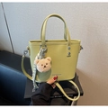 Détail du sac seau en cuir vert citron avec un charmant pendentif d'ours brun en peluche - Vert Fruit