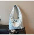 Detail of light blue hobo bag with vintage texture and stylish ribbon bow on a book - Blue