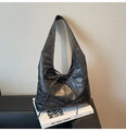 Close-up of black leather tote bag with stylish bow detail and textured finish - Black