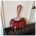 Gros plan du sac hobo en cuir verni rouge brillant avec boucles argentées et poches - Rouge