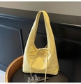Yellow faux leather hobo bag with ribbon knot detail on a black vintage chair - Yellow