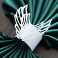 Macro detail of laser-cut white paper napkin ring with elegant wing design on green fabric - White