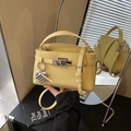 Gele handtas van kiezelleder met zilveren sluiting en hartvormige hanger in de hand - Geel (Met Hanger)