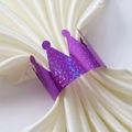 Détail d'un rond de serviette couronne à paillettes mauves sur du satin blanc doux - Violet Pailleté