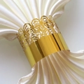 Detailed view of golden crown hollow lace napkin ring on white satin fabric for party - Mirror Gold