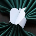 Detail of apple-shaped white cardstock napkin ring on a dark green napkin and wooden table - 17.5cm / White