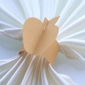 Detailed view of champagne gold apple napkin ring on a white folded cloth napkin - 17.5cm / Gold
