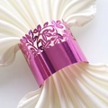 Macro shot of magenta laser-cut napkin ring with intricate floral patterns on white satin - Nail Powder