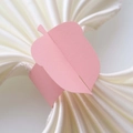 Detailed view of pink leaf-shaped paper napkin ring on a white satin cloth - Pink