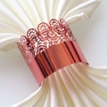 Close-up of rose gold lace napkin ring with intricate hollow laser-cut floral patterns - Mirror Apple Red