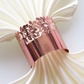 Detail of rose gold laser-cut napkin ring with floral hollow patterns on white satin - Mirror Rose Gold