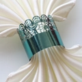 Macro shot of laser-cut teal napkin ring with intricate crown lace and metallic finish - Mirror Indigo