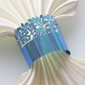 Detail of laser-cut floral napkin ring with iridescent metallic finish on white fabric - Rainbow Blue