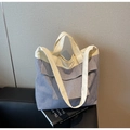 Dettaglio della borsa tote a righe bianche e blu con manici crema e tasca a patta - Taglia unica / A righe