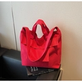 Gros plan d'un sac cabas en toile rouge avec poche à rabat sur un canapé noir élégant - Bordeaux