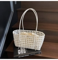 White woven hollow-out underarm tote bag with drawstring inner pouch on dark wood stairs - White
