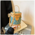 Detail of denim bucket bag featuring leather trim, gold zippers, and jacquard pattern - Blue