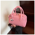 Vue détaillée du sac bowling en cuir rose avec grain litchi et pendentif baleine - Rose