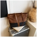 Grand sac cabas en tweed bicolore avec anses en cuir posé sur une valise argentée - Noir et Marron