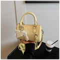 Détail du sac cylindre Boston jaune crème avec texture froissée et breloque nœud perlé - Jaune avec Pendentif