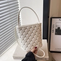 White quilted bucket bag with metal studs and chain strap in a minimalist setting - White
