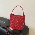 Red quilted bucket bag with rhinestones and chain strap on leather sofa - Red