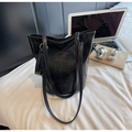 Close-up of black faux crocodile texture tote bag with slim straps in an office setting - Black