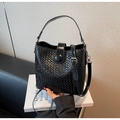 Close-up of black woven leather bucket bag with silver metal snap and shoulder strap detail - Black