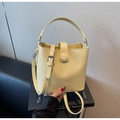 Detail of light yellow woven bucket bag showing textured pattern and adjustable strap - Yellow