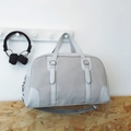 Light gray canvas Boston bag with leather trim and adjustable strap on a wall hook - Gray