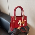 Red woven texture handbag featuring a white Pegasus charm and woven top handle strap - With Charm / Burgundy