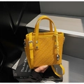 Macro detail of yellow woven leather texture on a stylish handbag with silver heart charm - Yellow