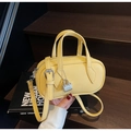 Detail of a mini yellow crossbody pillow bag showing high-quality pebble leather texture - Yellow