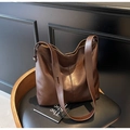 Close-up of brown pebbled leather texture and adjustable strap on a vintage hobo bag - Coffee