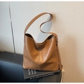 Detail of a large brown hobo bag with vintage leather texture on decorative books - Brown
