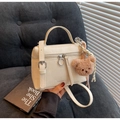 Close-up of cream textured crossbody bag with plush bear charm on grey corduroy - Off White