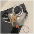 Close-up of silver bucket bag with plush bear charm on a dark grey blazer background - Silver