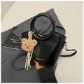 Detail of black glossy bucket bag with round handle and cute teddy bear charm accessory - Black