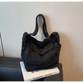Detail of black canvas shoulder bag showing worn fringe edges and large utility pockets - Black