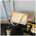 Detail view of cream cylinder shoulder bag with lychee texture and colorful letter charm - Beige With Charm